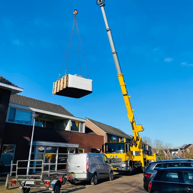 Hijskraan tilt een spa over het huis