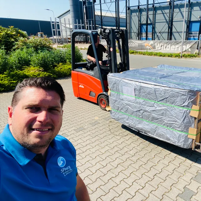 Medewerker van Spaweb bij een ingepakte spa op een heftruck