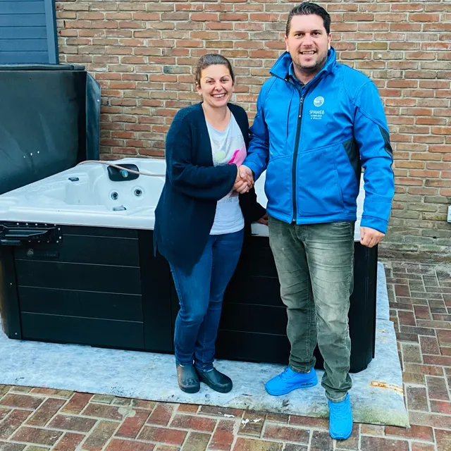 Klant en medewerker van Spaweb bij een nieuwe spa voor een bakstenen muur
