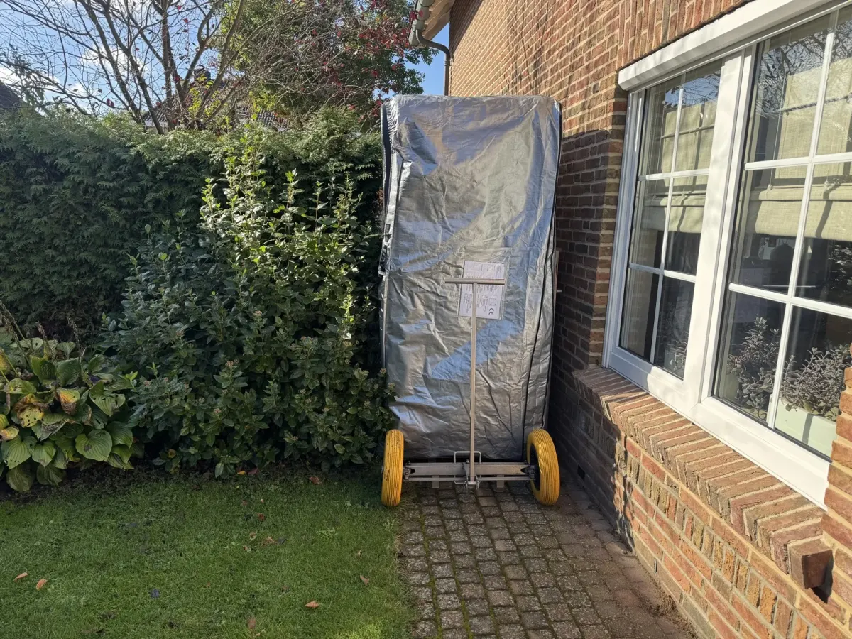Ingepakte spa op zijn zijkant op een transportkar naast een huis
